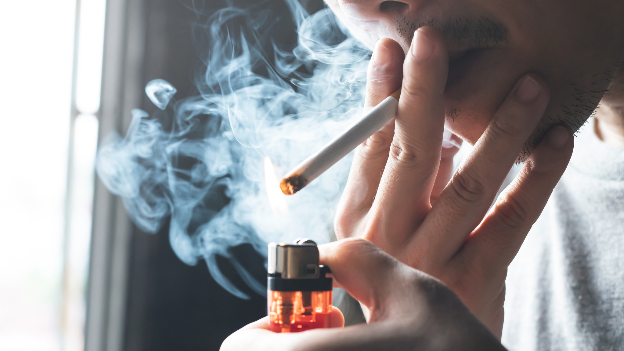 A man is smoking a cigarette at home